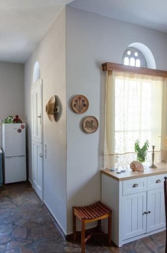 a kitchen with white cabinets and a window and a table at m͟͞a͟͞t͟͞a͟͞t͟͞h͟͞i͟͞a͟͞ GuestHouse Tinos in Triandáros
