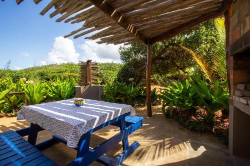 a table and chairs under a pergola at Zona Braza Beach Lodge in Chizavane