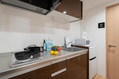 a kitchen with a sink and a frying pan on a stove at Hotel Abitare Namba West in Osaka
