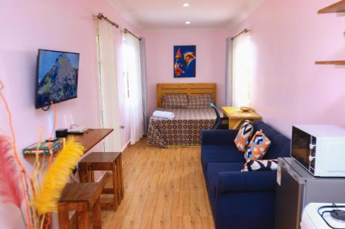 a living room with a blue couch and a bed at The Red Container-Off Grid in Ngong