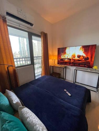 a bedroom with a large blue bed and a flat screen tv at Beautiful 1BR balcony w/65UHDTV Wifi Netflix, pool in Manila