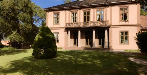 a large pink house with a tree in the yard at Frogner Hovedgård in Skien
