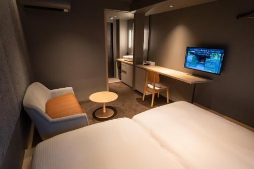 a hotel room with a bed and a chair and a desk at Onn Yuda Onsen in Yamaguchi