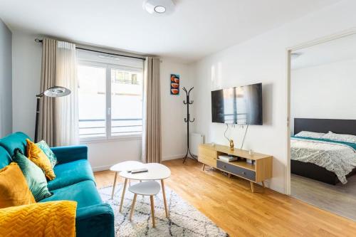 uma sala de estar com um sofá azul e uma cama em Cosy appart entre Paris et Disneyland em Villiers-sur-Marne