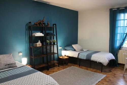 sypialnia z 2 łóżkami i niebieską ścianą w obiekcie ARTS & Passion w mieście Mirambeau