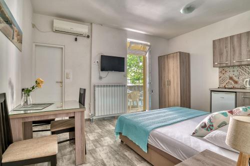 a bedroom with a bed and a desk and a television at Apartmani Agape in Petrovac na Moru