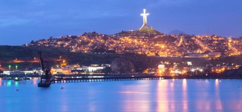a city with a cross on a hill at night at Jardin del Mar SPA & Enjoy in Coquimbo