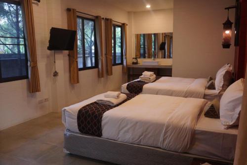 a room with three beds and a bathroom with a mirror at ANANTAYA CHIANGMAI BOUTIQUE HOTEL in Chiang Mai