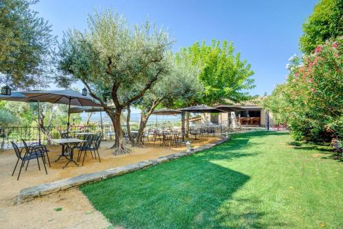 a garden with tables and chairs and umbrellas at Vilajoun in Joucas