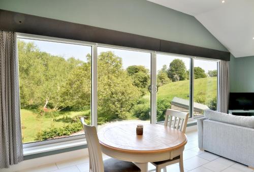 a living room with a table and chairs and a large window at Boat House Lodge in Shrewsbury
