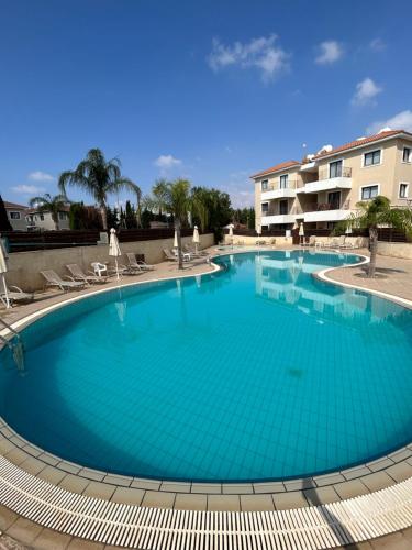 a large blue swimming pool with chairs and a building at Paros 1 bedroom APT Kyklades in Paralimni