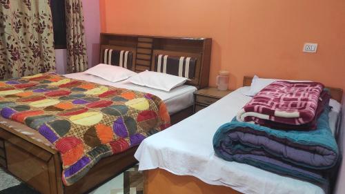 a bedroom with two beds with a colorful quilt on them at Laxmi Homes in Sari
