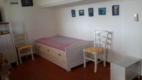 um pequeno quarto com uma cama e 2 cadeiras em Dino&Fanny Villasimius em Villasimius