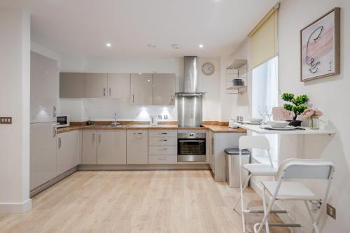 uma cozinha com armários brancos e uma mesa e cadeiras em Deluxe Condo Beside 02 Arena and Central London em Londres