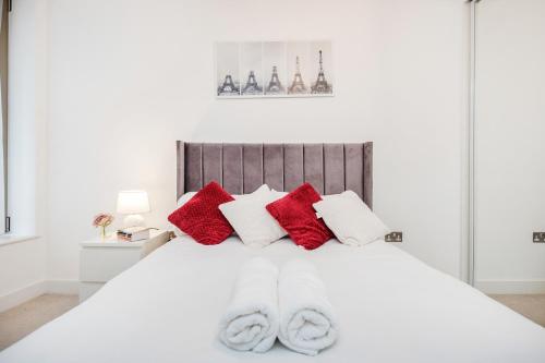 a white bedroom with red and white pillows on a bed at Deluxe Condo Beside 02 Arena and Central London in London