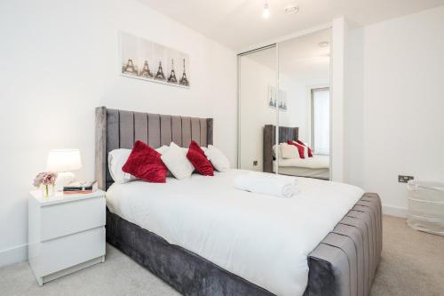 um quarto com uma grande cama branca com almofadas vermelhas em Deluxe Condo Beside 02 Arena and Central London em Londres
