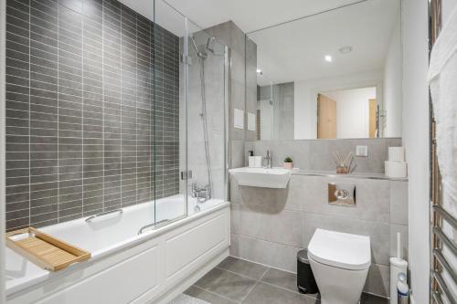 a bathroom with a tub and a toilet and a sink at Deluxe Condo Beside 02 Arena and Central London in London