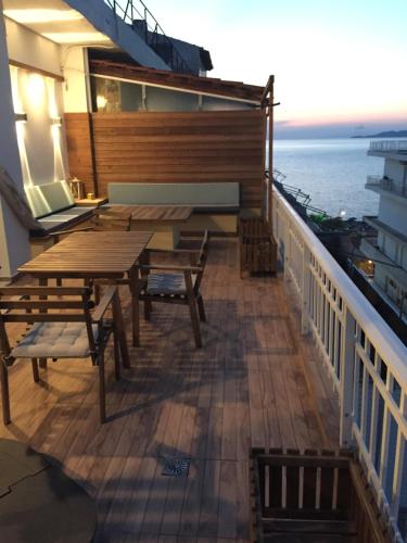 un balcón con mesas de madera y sillas en un crucero en On the beach. Walking distance from all amenities, en Korinthos