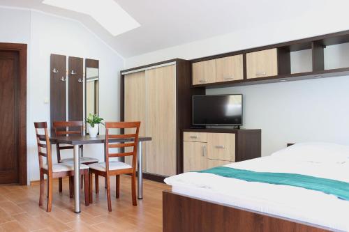 1 dormitorio con 1 cama, mesa y sillas en Pokoje gościnne Trzy Młyny, 