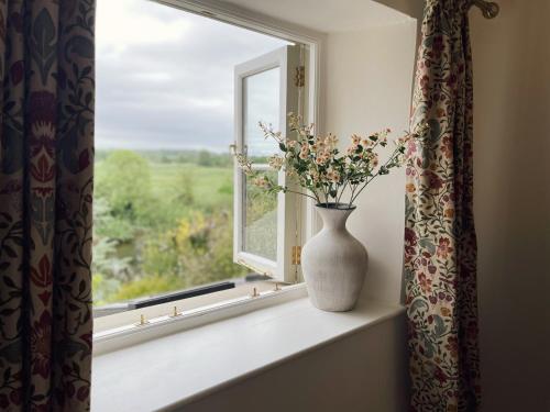 a vase sitting on a window sill with a vase at The Little Chantry - Hot Tub, Riverside, Pet Friendly in West Tanfield
