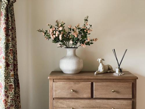 a vase of flowers sitting on top of a dresser at The Little Chantry - Hot Tub, Riverside, Pet Friendly in West Tanfield