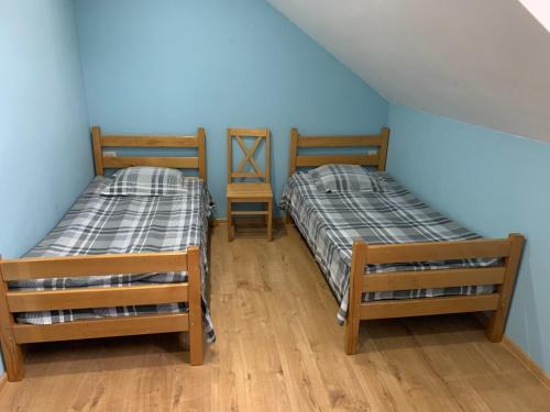 two beds in a room with blue walls and wooden floors at Eco family guest house in Mlashe