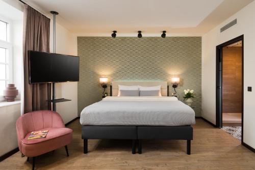une chambre d'hôtel avec un lit et une chaise rose dans l'établissement master Mirabell, à Salzbourg