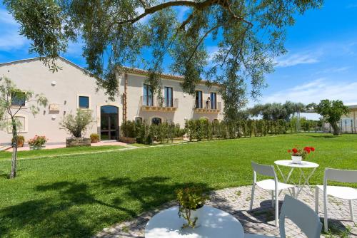 a garden with a table and chairs in front of a house at Nèroli Bio Relais in Catania
