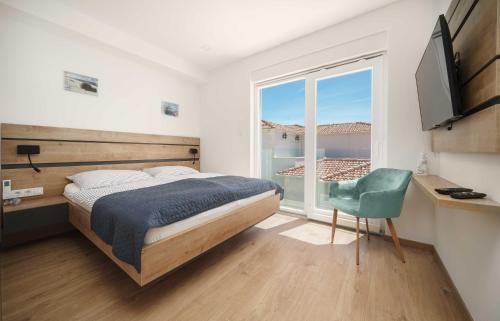 ein Schlafzimmer mit einem Bett, einem Fenster und einem Stuhl in der Unterkunft Pinia Apartments in Vodice