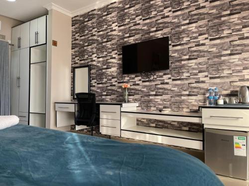 1 dormitorio con TV en una pared de piedra en The Ace Hotel en Lusaka