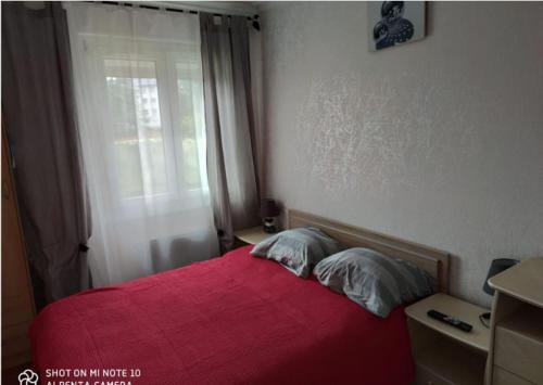 - une chambre avec un lit rouge et une fenêtre dans l'établissement chez Natalie et Serge, à Lannion