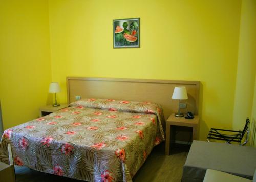 a bedroom with a bed and two tables with lamps at Hotel Cristallo in Lignano Sabbiadoro