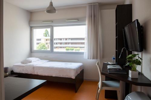 um quarto com uma cama, uma secretária e uma janela em Zenitude Hôtel-Résidences Les Hauts Du Chazal em Besançon