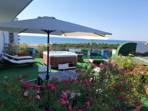 a patio with an umbrella and chairs and flowers at Hotel Cristallo in Lignano Sabbiadoro