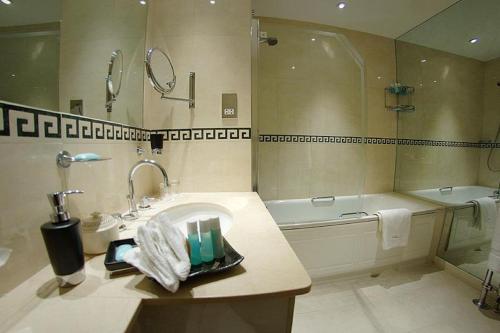 a bathroom with a sink and a bath tub at The Beaufort in London