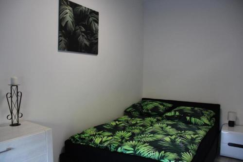 Un dormitorio con una cama con hojas verdes. en Domki do wynajęcia, en Wolsztyn