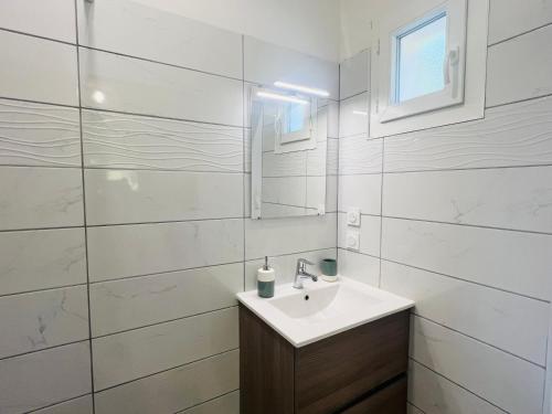Gite la Canague Neuve في Montady: حمام أبيض مع حوض ومرآة