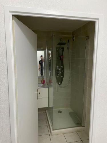 La salle de bains est pourvue d'une douche en verre avec une personne dans le miroir. dans l'établissement Résidence les Goélettes, logement RDC à 30 m de la plage, à Saint-Cyprien