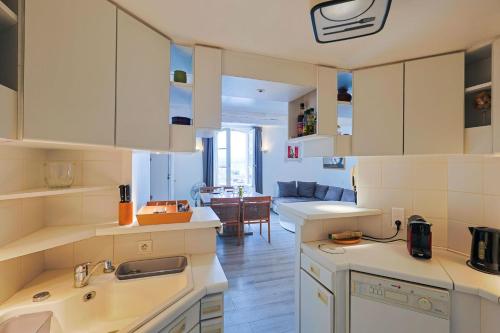 une cuisine avec des armoires blanches et un salon dans l'établissement Sailing Apartment by Halldis, à Saint-Tropez