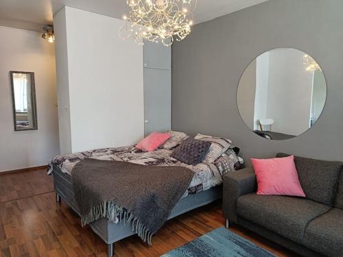 a bedroom with a bed and a mirror and a couch at Ihana yksiö joen ja torin lähellä in Joensuu