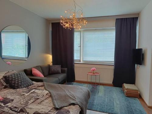 a bedroom with a bed and a couch and a mirror at Ihana yksiö joen ja torin lähellä in Joensuu