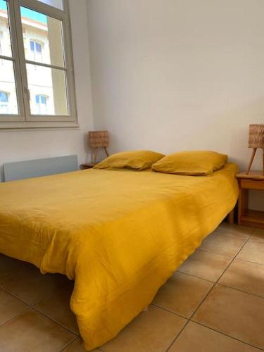 - un lit jaune avec 2 oreillers dans l'établissement Studio Soulac centre et plage, à Soulac-sur-Mer