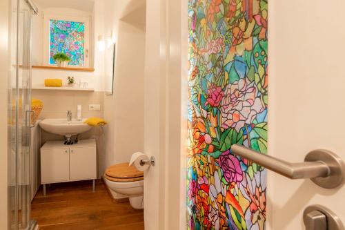 a bathroom with a toilet and a colorful shower curtain at Roomerie im Zentrum in Sulzbach-Rosenberg