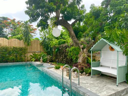 a swimming pool with a bench next to a tree at Comfy Boutique House in Chiang Mai