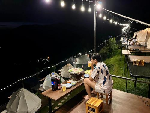 Una donna seduta a tavola che mangia cibo di notte di Heaven Khaokho (เฮฟเว่น) a Khao Kho