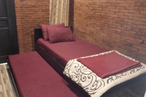 a bed sitting against a brick wall with a pillow at GRHA PAWITRA TROWULAN in Trowulan