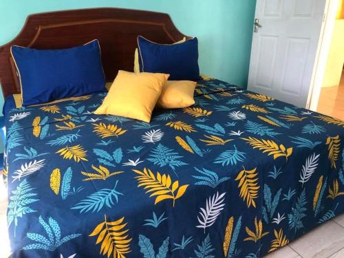 een bed met een blauw dekbed met gele kussens bij El Paraiso in La Gaulette