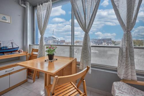 une cuisine avec une table et des chaises ainsi qu'une grande fenêtre dans l'établissement Galys - Appt à 1 km de la plage, à Courseulles-sur-Mer