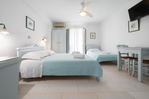 a white bedroom with two beds and a table at Castello studios in Agia Anna Naxos