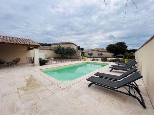 una piscina con 2 tumbonas junto a una casa en LE MAS DE MAELLOU - 12 COUCHAGES - ENCLAVE DES PAPES, en Grillon